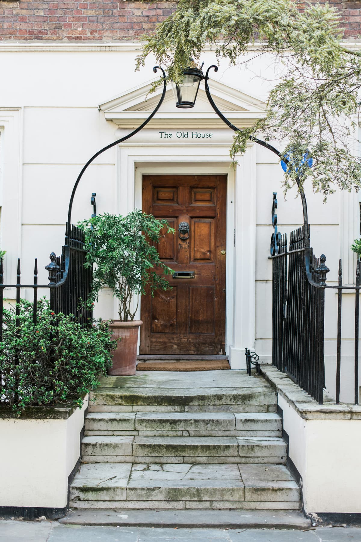 Panelled wooden front door with black iron railings and gate